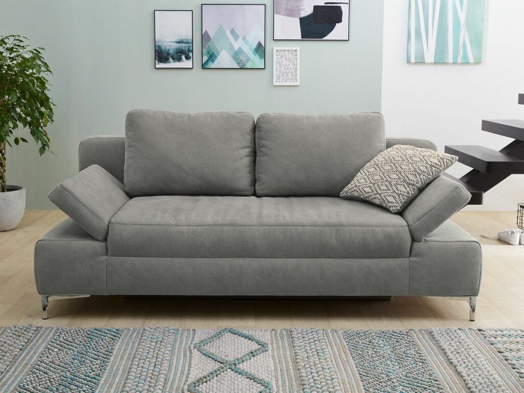Graues Zweisitzer-Sofa vor hellgrüner Wand mit Wandbildern