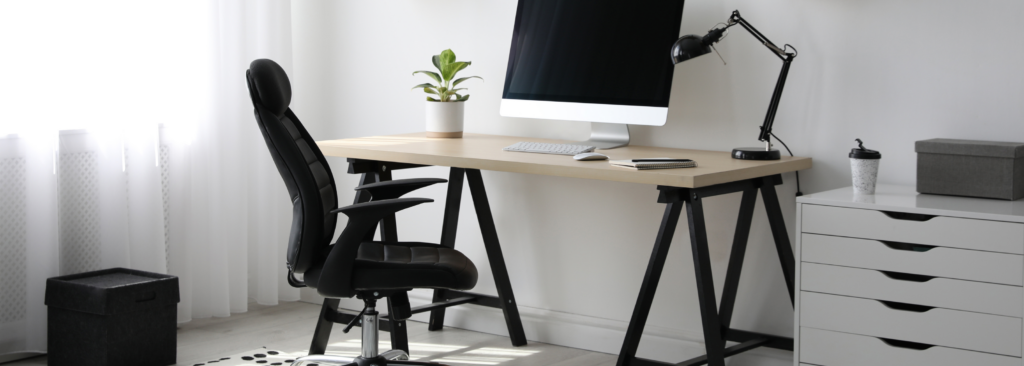 Schreibtisch mit Bürostuhl. Computer und Lampe auf Schreibtisch. Schwarz-weiße Einrichtung.